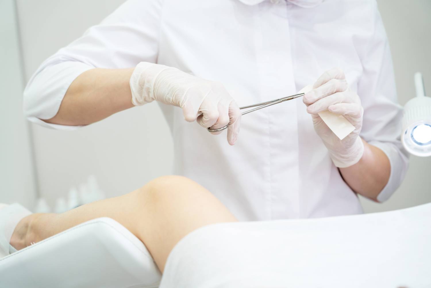 Gynecologist opening up band aid with forceps